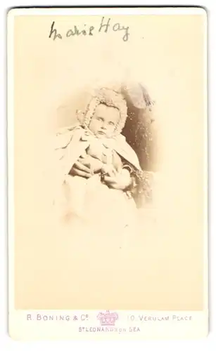 Fotografie R. Boning & Co., St. Leonards on Sea, Portrait niedliches Kleinkind in hübscher Kleidung mit Mütze