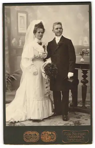 Fotografie MAx Seifert, Freiberg i. S., junges sächsisches Ehepaar im Hochzeitskleid und Anzug mit Zylinder, Brautstrauss