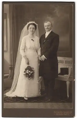 Fotografie Richard Bassler, Oberoderwitz, Eheleute im Hochzeitskleid und Anzug mit Zylinder auf der Bank, Brautstrauss