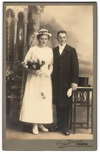 Fotografie Oscar Krämer, Zittau, Hochzeitspaar mit Brautstrauss, Hochzeitskleid und Anzug vor einer Studiokulisse
