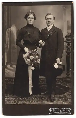 Fotografie Carl Meier, Passau, älteres Brautpaar im schwarzen Hochzeitskleid und Anzug mit Zylinder in der Hand