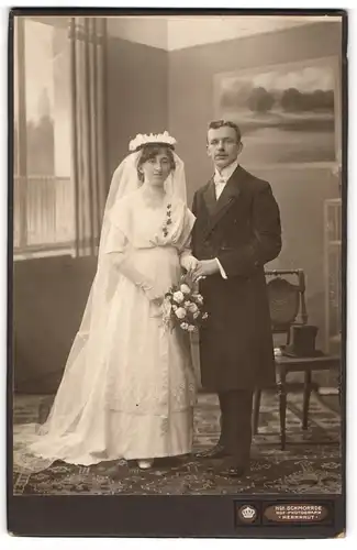 Fotografie Hch. Schmorrde, Herrnhut, junge Eheleute im Hochzeitskleid und Anzug, Brautstrauss