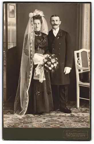 Fotografie A. Kryzwinski, Grossröhrsdorf, Eheleute im schwarzen Brautkleid und Anzug mit Schleier und Brautstrauss