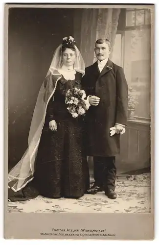 Fotografie Ateleir Wilhelmstadt, Magdeburg, junges Ehepaar im schwarzen Brautkleid und Anzug, Brautstrauss