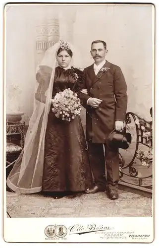 Fotografie Otto Böhm, Passau, Eheleute im schwarzen Brautkleid und Anzug mit Brautstrauss