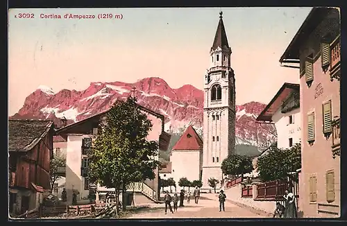 AK Cortina D`Ampezzo, Strassenpartie mit Blick nach der Kirche und Dolomiten in der Dämmerung