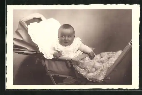 Foto-AK Niedliches Baby sitzt mit Felldecke im Kinderwagen