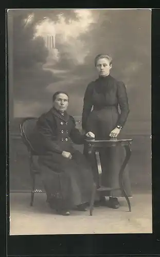 Foto-AK Portrait von zwei bürgerlichen Damen am Tisch vor einer Studiokulisse