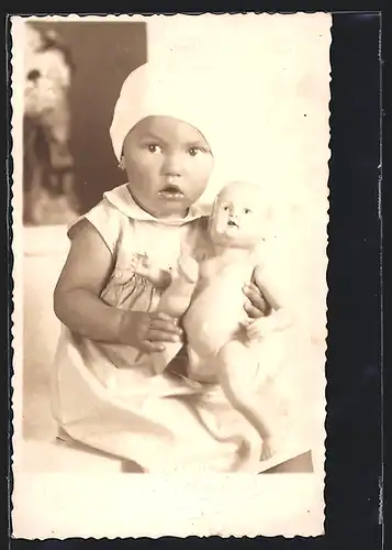 Foto-AK Erstauntes Kind mit nackter Puppe im Arm