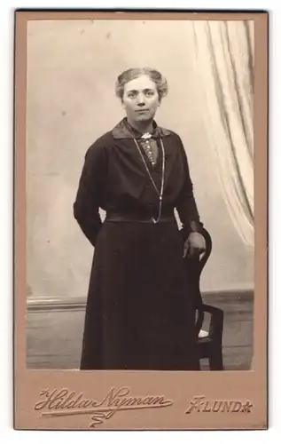 Fotografie Hilda Nyman, Alunda, Portrait elegant gekleidete Dame an Stuhl gelehnt