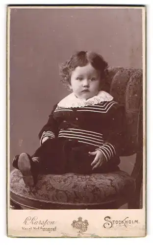 Fotografie L. Larsson, Stockholm, Portrait kleines Mädchen im Samtkleid auf Stuhl sitzend