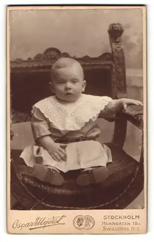 Fotografie Oscar Ellqvist, Stockholm, Portrait niedliches Kleinkind im hübschen Kleid sitzt auf einem Stuhl