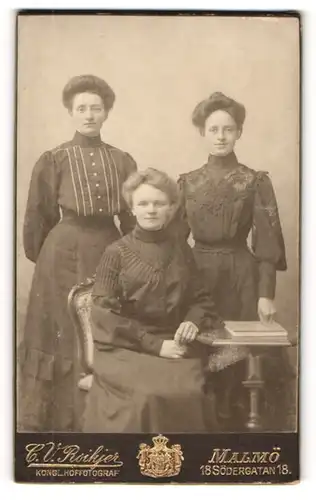Fotografie C. V. Roikjer, Malmö, Portrait drei junge Damen in modischer Kleidung am Tisch