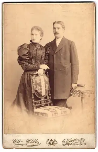 Fotografie Otto Witte, Berlin-SO, Portrait modisch gekleidetes Paar an Stuhl gelehnt