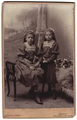 Fotografie Wilhelm Stein, Berlin, Portrait zwei kleine Mädchen in modischen Kleidern