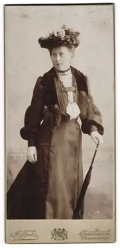 Fotografie J. Fuchs, Berlin-Charlottenburg, Portrait junge Dame im eleganten Kleid mit Hut und Schirm