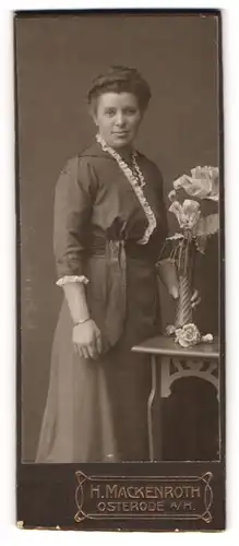 Fotografie H. Mackenroth, Osterode a. H., Frau im Kleid umklammert Vase mit Rosen