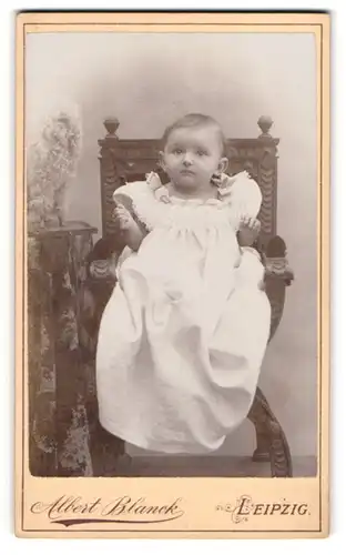 Fotografie Albert Blanck, Leipzig, Portrait Kleinkind in Kleid auf Sitzmöbel
