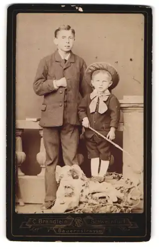 Fotografie C. Brändlein, Schweinfurt, Portrait junger Mann im Anzug und kleiner Junge mit Peitsche