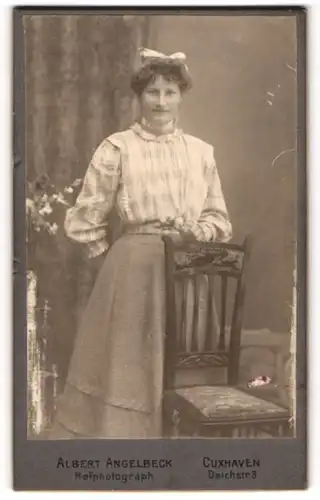 Fotografie Albert Angelbeck, Cuxhaven, Portrait junge Dame in karierter Bluse mit Blume an Stuhl gelehnt