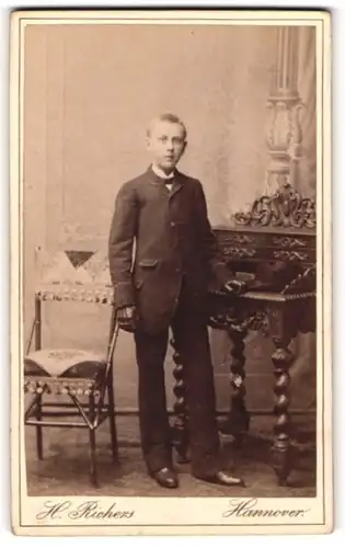 Fotografie H. Richers, Hannover, Portrait junger Mann im Anzug mit Fliege und Handschuhen