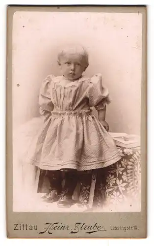 Fotografie Heinr. Strube, Zittau i / S., Portrait kleines Mädchen im hübschen Kleid auf Stuhl stehend