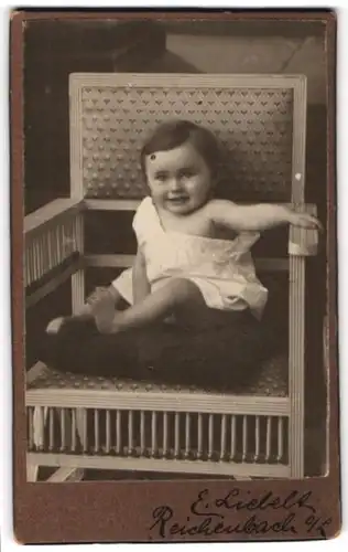 Fotografie E. Liebelt, Reichenbach O / L, Portrait niedliches Kleinkind im weissen Hemd auf Kissen sitzend