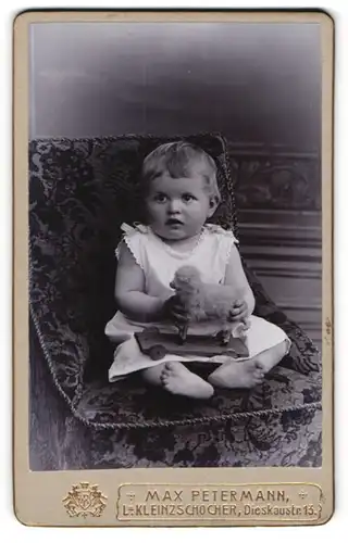 Fotografie Max Petermann, Leipzig-Kleinzschocher, Portrait sitzendes Kleinkind im weissen Hemd mit Spieltier