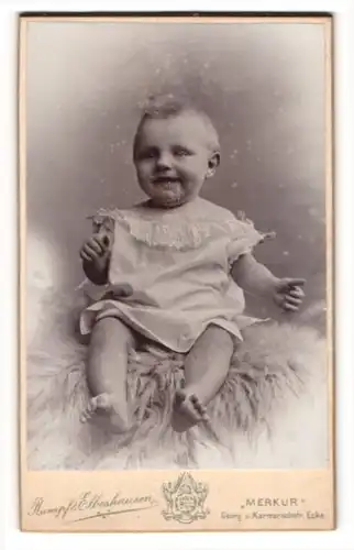 Fotografie Rumpf & Elbeshausen, Hannover, Portrait niedliches Kleinkind im weissen Hemd auf Fell sitzend