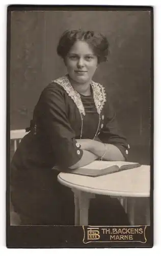Fotografie Th. H. Backens, Marne, Portrait bürgerliche Dame mit Buch am Tisch sitzend