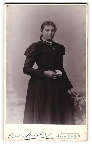 Fotografie Oscar Meister, Bautzen, Portrait bürgerliche Dame mit Blume an Tisch gelehnt