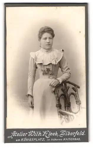 Fotografie Wilh. Kleeb, Elberfeld, Portrait junge Dame im eleganten Kleid an Stuhl gelehnt