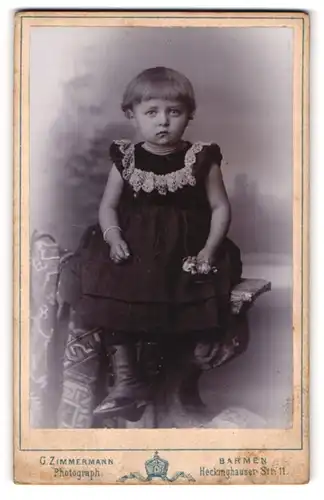 Fotografie G. Zimmermann, Barmen, Portrait kleines Mädchen im hübschen Kleid auf Tisch sitzend