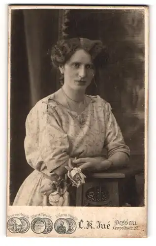 Fotografie L. K. Jué, Dessau, Portrait bürgerliche Dame mit Rose an Tisch gelehnt