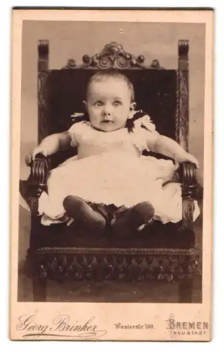Fotografie Georg Brinker, Bremen, Portrait niedliches Kleinkind im weissen Kleid auf Stuhl sitzend