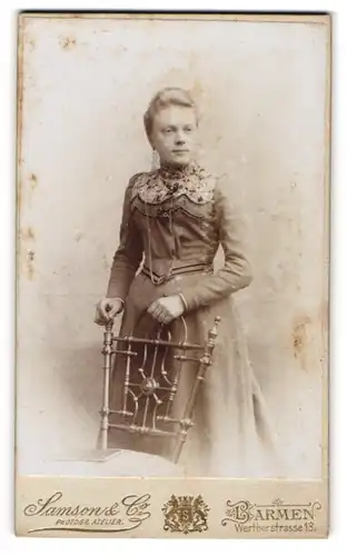 Fotografie Samson & Co., Barmen, Portrait junge Dame im eleganten Kleid an Stuhl gelehnt