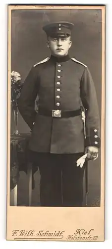 Fotografie F. Wilh. Schmidt, Kiel, Portrait Soldat in Uniform mit Schirmmütze und Handschuhen