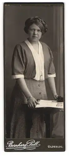 Fotografie Bernhard Prill, Oldesloe, Portrait junge Dame in modischer Kleidung mit Zeitung an Tisch gelehnt