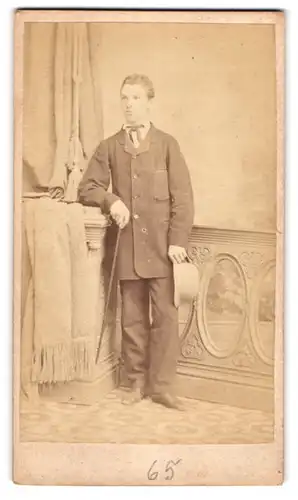 Fotografie unbekannter Fotograf und Ort, junger Mann V. Linz im Mantel mit Stock und Hut, 1865