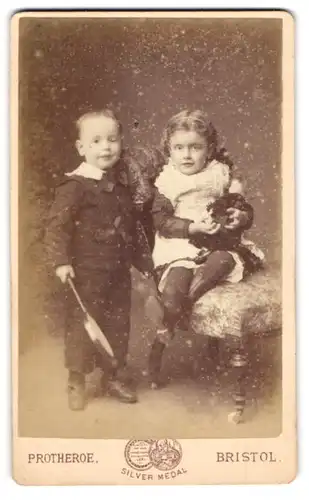 Fotografie Protheroe, Bristol, zwei junge Kinder Boby und Maud Pring mit Puppe im Arm