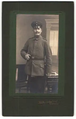 Fotografie Wilh. Nottebroch, Gütersloh, Soldat in Uniform mit Schirmmütze und Koppelschloss