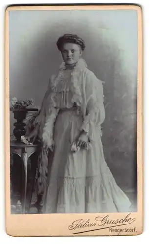 Fotografie Julius Grusche, Neugersdorf i. S., Junge Frau im weissen Kleid stehend an einem Beistelltisch