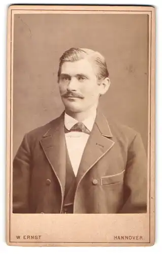 Fotografie W. Ernst, Hannover, Portrait eines jungen Mannes im Anzug mit Seitenscheitel
