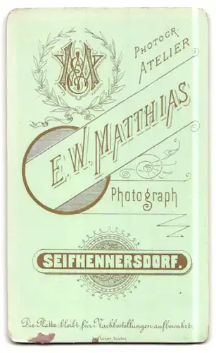 Fotografie E. W. Matthias, Seifhennersdorf, Junger Bursche trägt einen Anzug und lehnt auf einem Tisch