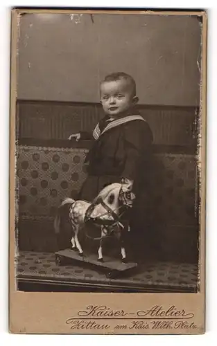 Fotografie Kaiser-Atelier, Zittau, Kleiner Junge in Matrosenuniform mit seinem Spielzeugpferd