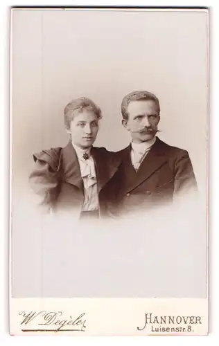 Fotografie W. Degèle, Hannover, Mann mit langem Schnauzbart und Frau in Kleid mit Faltenwurf