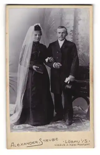 Fotografie Alexander Strube, Löbau i. S., Portrait elegant gekleidetes Paar mit Schleier, Gebetsbuch und Zylinder