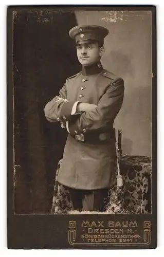 Fotografie Max Baum, Dresden-N, Portrait Soldat in Uniform mit Schirmmütze und verschränkten Armen