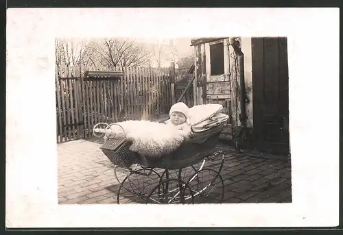 Fotografie Baby mit Felldecke im Kinderwagen liegend