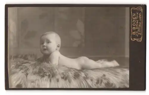 Fotografie B. Boden, Zittau, Portrait niedliches Baby liegt auf einem Fell